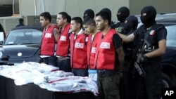 State investigation agents escort the five arrested men in connection with an attack at the casino last week that killed 52 people, during a presentation in Monterrey, August 30, 2011
