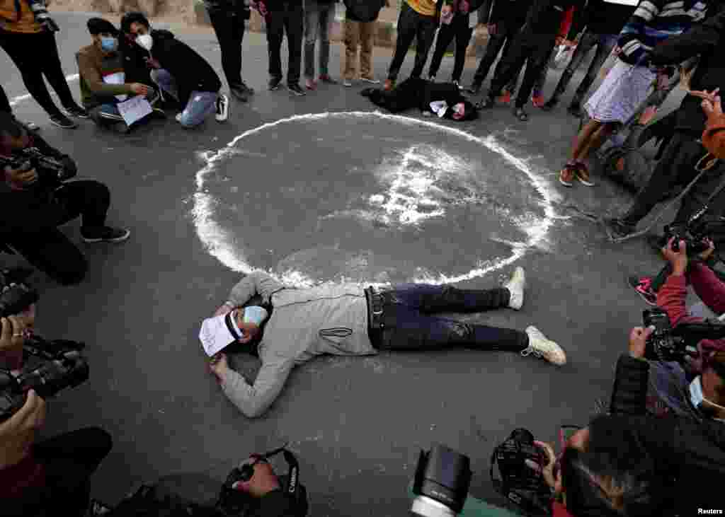 Protesters lie down on the road next to the Nepalese word that means parliament during a protest against the dissolution of parliament, in Kathmandu, Nepal.