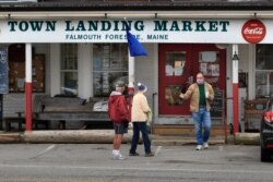 FILE - Customers chat outside the Town Landing Market in Falmouth Foreside, Maine, April 9, 2020, as the town's streets are empty due to the coronavirus pandemic.
