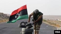 Seorang anggota anti-Gaddafi menancapkan bendera kemerdekaan Libya di pos pemeriksaan terakhir menuju Bani Walid yang sebelumnya dikuasai oleh pasukan Gaddafi (6/9).