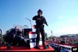 Republican presidential candidate former President Donald Trump is surrounded by U.S. Secret Service agents on stage at a campaign rally, July 13, 2024, in Butler, Pennsylvania.