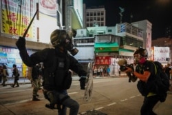 FILE - A journalist records video of a riot police officer charging towards protesters during a clash in Hong Kong, Oct. 21, 2019.