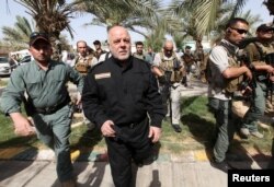 FILE - Iraq's Prime Minister Haider al-Abadi (front 2nd L) walks during his visit to an Iraqi army base in Camp Tariq near Fallujah, Iraq, June 1, 2016.