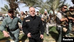 FILE - Iraq's Prime Minister Haider al-Abadi (front 2nd L) walks during his visit to an Iraqi army base in Camp Tariq near Fallujah, Iraq, June 1, 2016. 