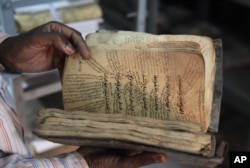 A man holds an ancient manuscript from Timbuktu that will need to be restored after being damaged by Islamic extremists in Bamako, Mali, Jan. 27, 2015.