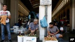 Two street vendors talk each other outside the main fish market of Athens, Aug. 20, 2018, on the day that Greece's eight-year crisis will be officially over. 