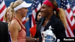 ນາງ Serena Williams ຈາກສະຫະລັດ (ຂວາ) ແລະ ນາງ Caroline Wozniacki ຈາກເດັນມາກ ລົມກັນໃນຂະນະທີ່ ພວກເຂົາເຈົ້າກຳລັງຖືຂັນລາງວັນ ຫຼັງຈາກການແຂ່ງຂັນ U.S. Open ປະຈຳປີ 2014 ຮອບຊິງຊະນະເລີດ ຍິງດ່ຽວ ໃນວັນທີ 7 ກັນຍາ 2014 ຢູ່ລັດ New York.