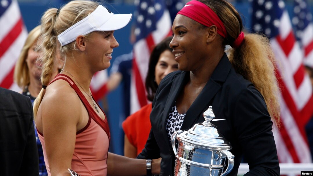 Serena Williams of the U.S. (R) and Caroline Wozniacki of Denmark chat as they hold their trophies following the women's singles finals match at the 2014 U.S. Open tennis tournament in New York, September 7, 2014. 