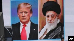A man walks by a huge screen showing U.S. President Donald Trump, left, and Iranian Supreme Leader Ayatollah Ali Khamenei, in Tokyo, Jan. 8, 2020. 