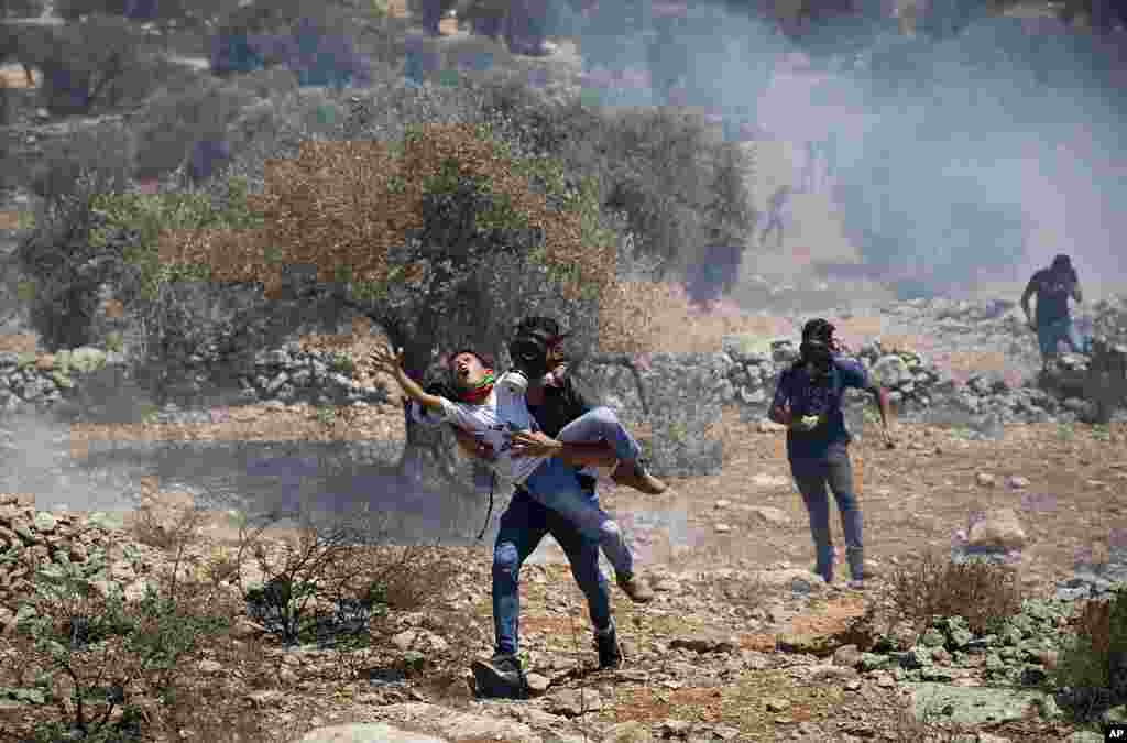 Palestinians carry a boy away from the gas tear canisters fired by Israeli soldiers during a protest against the West Bank Jewish settlement outpost of Eviatar that was rapidly established last month, near the West Bank city of Nablus.