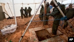 Israeli soldiers stand around the opening of a hole that leads to a tunnel that the army says crosses from Lebanon to Israel, near Metula, Dec. 19, 2018.