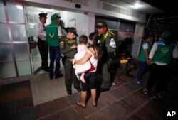 En esta foto del 26 de junio de 2018, la policía acompaña a la venezolana Eliusmar Guerrero, de 17 años, y su hija de 1 año y medio, a una oficina de bienestar infantil, donde puede conseguir comida y un lugar temporal para dormir en Cúcuta, Colombia.