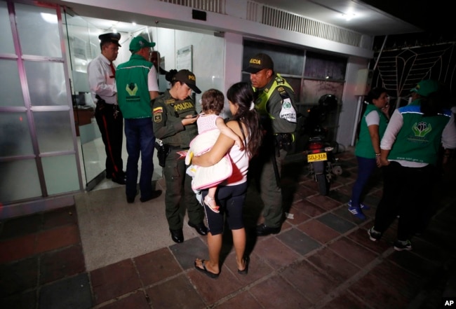 En esta foto del 26 de junio de 2018, la policía acompaña a la venezolana Eliusmar Guerrero, de 17 años, y su hija de 1 año y medio, a una oficina de bienestar infantil, donde puede conseguir comida y un lugar temporal para dormir en Cúcuta, Colombia.