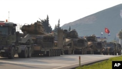 FILE - Turkish military trucks carrying tanks and personnel carriers are destined for the border with Syria, Jan. 14, 2019. 