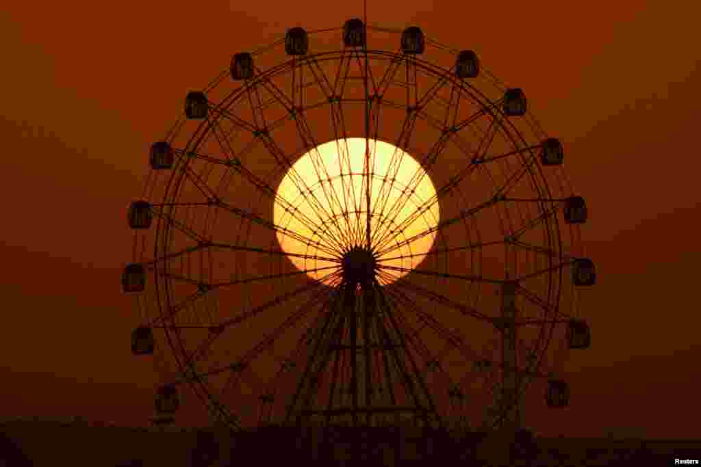 The sun is seen rising behind a skywheel in Korla, Xinjiang Uighur Autonomous Region, China.