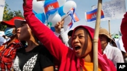 Cambodian garment workers shout slogans during a gathering to mark May Day celebrations in Phnom Penh, Cambodia, Friday, May 1, 2015. Garment workers staged a rally to demand higher wage and better working condition. The placard at right in the background reads: "Demanding the government urgently set up the labor court." (AP Photo/Heng Sinith)