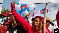 Cambodian garment workers shout slogans during a gathering to mark May Day celebrations in Phnom Penh, Cambodia, Friday, May 1, 2015. Garment workers staged a rally to demand higher wage and better working condition. The placard at right in the background reads: "Demanding the government urgently set up the labor court." (AP Photo/Heng Sinith)