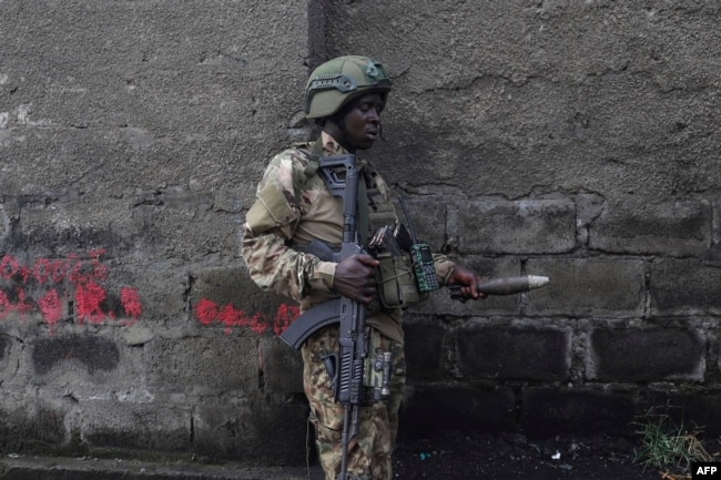 A member of the M23 rebel group picks an unexploded mortar shell from the floor during a cleanup exercise in Goma, Democratic Republic of Congo, on Feb. 1, 2025.