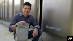 Joe Tavi, Bloom Energy senior director of manufacturing, holds a refurbished ventilator as he kneels beside fuel cells, April 1, 2020, in Sunnyvale, Calif.