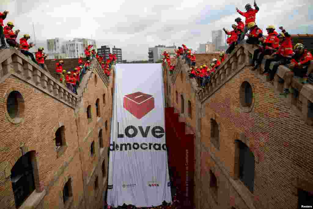 Firemen react as they hang a huge banner in favor of the banned October 1 independence referendum at Catalonia's History Museum in Barcelona, Spain.