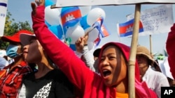 Cambodian garment workers shout slogans during a gathering to mark May Day celebrations in Phnom Penh, Cambodia, Friday, May 1, 2015. Garment workers staged a rally to demand higher wage and better working condition. The placard at right in the background reads: "Demanding the government urgently set up the labor court." (AP Photo/Heng Sinith)