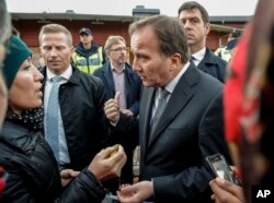 Prime Minister Stefan Lofven, right, talks to local people near the school Thursday afternoon where a masked man wielding what looked like a sword stabbed four people Thursday October 22, 2015, in Trollhattan, Southern Sweden.
