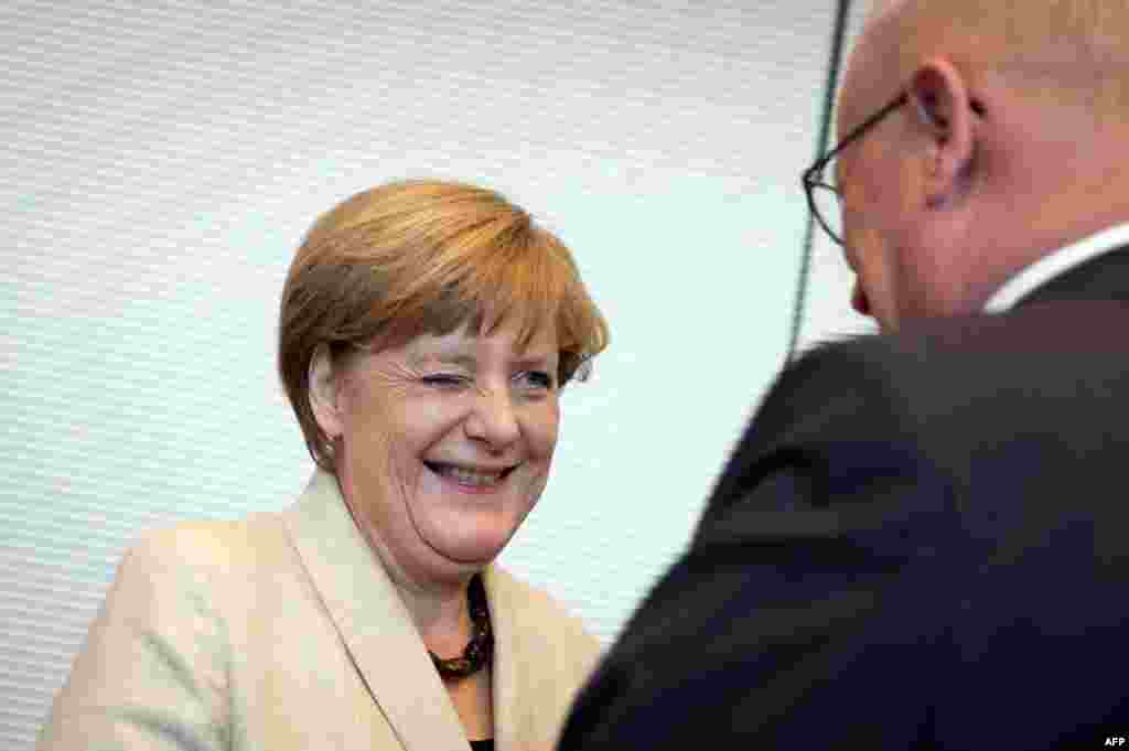 독일 연립 여당 원내 회의에 참석한 앙겔라 메르켈 총리가 볼커 카우더 기독민주당(CDU) 원내대표와 인사하며 윙크하고 있다.