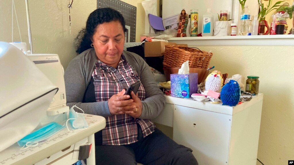 Rosalidia Dardon, 54, looks at a picture of her daughter in El Salvador as she sits in a refugee house in Texas, awaiting asylum or a protected immigration status on Nov. 4, 2021. (Acacia Coronado/Report for America via AP)