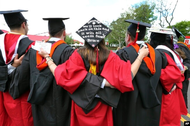 FILE - In this May 15, 2016, photo, students embrace as they arrive for the Rutgers graduation ceremonies in Piscataway, N.J. More Americans are getting buried by student debt, causing delays in home ownership, limiting how much people can save and leaving taxpayers at risk as many loans go unpaid.