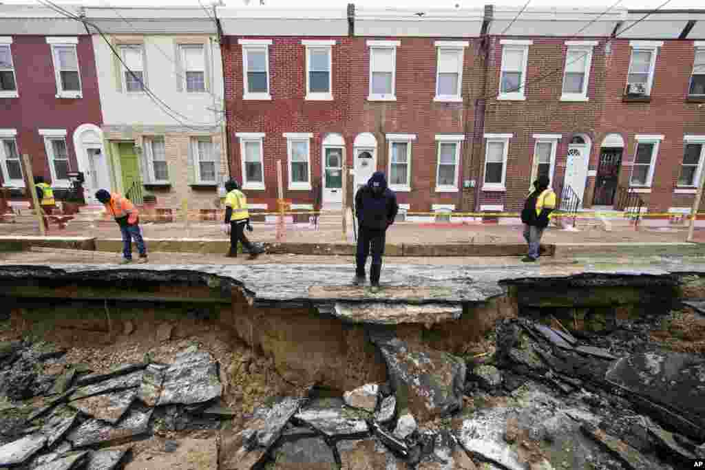 Workers inspect a sinkhole in Philadelphia, Pennsylvania.&nbsp;The Philadelphia Water Department said a water main break caused the sinkhole to open up on the street.