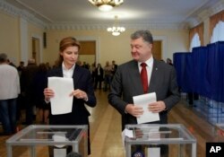 Ukrainian President Petro Poroshenko, right, and his wife, Maria, right, cast their ballots at a polling station during local election in Ukraine, Oct. 25, 2015.