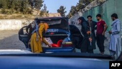 FILE - Taliban fighters search a car at a checkpoint in Kabul, Afghanistan, Sept. 14, 2021. 