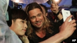 U.S. actor Brad Pitt poses for a photo with a fan upon arrival at the South Korea premiere of his latest film "World War Z" in Seoul on June 11, 2013.