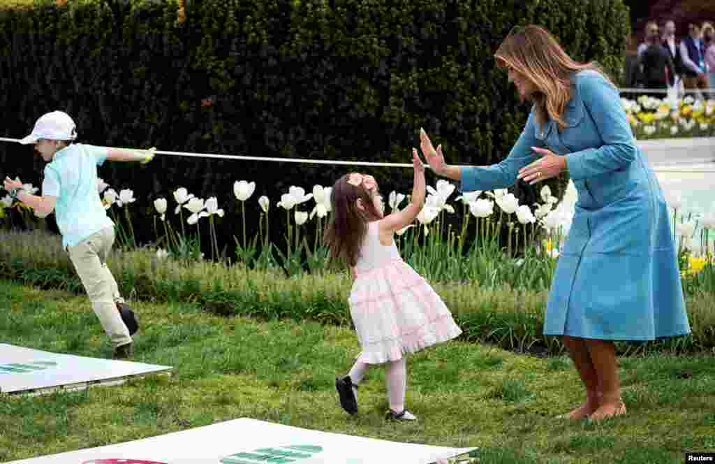 U.S. first lady Melania Trump high fives a child at the hopscotch station during the 2019 White House Easter Egg Roll on the South Lawn of the White House in Washington, D.C.