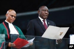 FILE - South African President Cyril Ramaphosa, right, takes the oath of office alongside Chief Justice Mogoeng Mogoeng at the Loftus Versfeld stadium in Pretoria, South Africa, May 25, 2019.