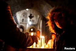 Worshippers light candles inside the Church of the Holy Sepulcher in Jerusalem's Old City, Dec. 24, 2017.