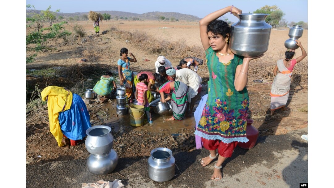 FILE - Indian Lambadi tribal villagers fill drinking water from a leaking pipe on a roadside at Chandampet Mandal in Nalgonda east of Hyderabad on April 25, 2016, in the southern Indian state of Telangana.