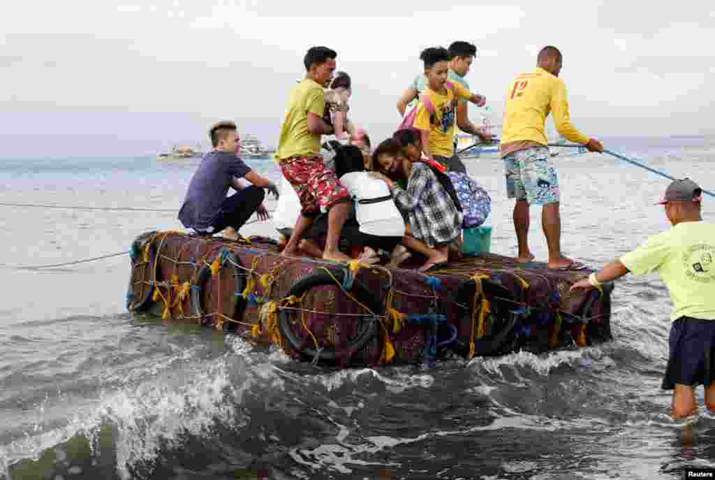 Stranded passengers ride on a makeshift raft after all ferry service were cancelled, a day after a Philippine vessel capsized because of bad weather in Infanta, Quezon in the Philippines, Dec. 22, 2017.