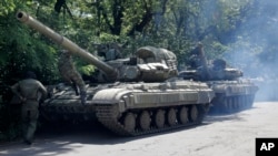 Pro-Russian troops prepare to travel in a tank on a road near the town of Yanakiyevo in eastern Ukraine, Friday, June 20, 2014. 