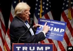 Campaign 2016 Trump: Republican presidential candidate Donald Trump holds up a "Christian Conservatives for Trump" sign at a rally, Wednesday, Sept. 28, 2016, in Council Bluffs, Iowa.