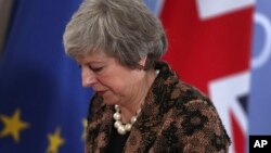 PM Inggris, Theresa May, melintas dekat bendera Inggris dan Uni Eropa saat meninggalkan konferensi pers di pertemuan puncak Uni Eropa di Brussels, 14 Des 2018 (foto: AP Photo/Fransisco Seco)