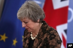 British Prime Minister Theresa May walks by the Union flag and the EU flag as she departs a media conference at an EU summit in Brussels, Dec. 14, 2018.