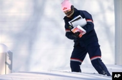 U.S. Postal Service letter carrier Jamie Jasmon struggles through snow and below zero temperatures while delivering the mail, Jan. 6, 2014, Springfield, Illinois.