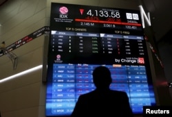 FILE - A trader stands in front of an electronic board at the Indonesia Stock Exchange (IDX) in Jakarta.