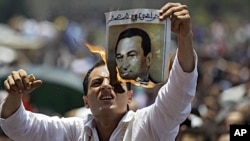 A man burns a picture of ousted Egyptian president Hosni Mubarak during a rally after Friday prayers in Tahrir Square, Cairo, July 1, 2011