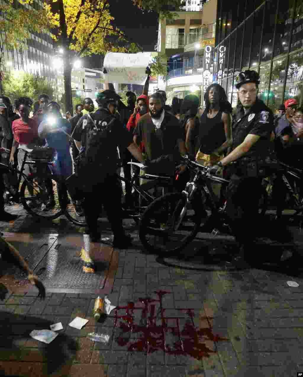 Polisi mengelilingi tempat genangan darah setelah seorang pria terluka dalam demonstrasi menentang penembakan fatal oleh polisi di Charlotte, North Carolina (21/9).&nbsp;(AP/Chuck Burton)