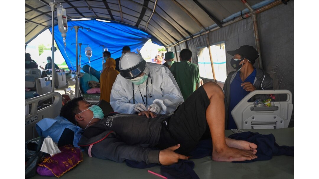 Seorang pria yang cedera akibat gempa 6,2 magnitudo yang terjadi pada 15 Januari sedang dirawat di tenda darurat di luar rumah sakit karena khawatir gempa susulan, di Kota Mamuju, Minggu, 17 Januari 2021. (Foto: Adek Berry/AFP)