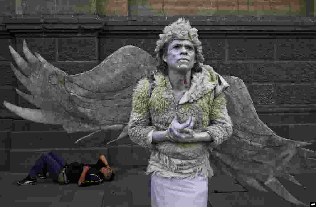 A street performer dressed as an angel holds still when a pedestrian tips him at the Plaza de Armas in Santiago, Chile, March 7, 2017.