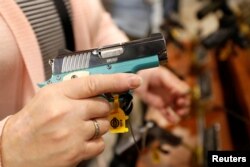 seorang perempuan memperhatikan pistol semi otomatis Kimber Micro Bel Air, pameran senjata api di Las Vegas, Nevada, 22 Januari 2019