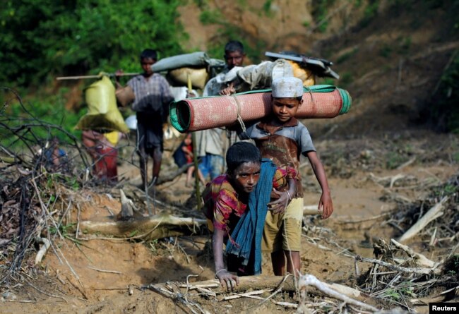 Rohingya refugees walk on a muddy path after crossing the Bangladesh-Myanmar border in Cox's Bazar, Bangladesh, Sept. 8, 2017.